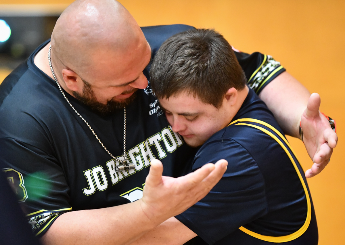 An athletes gets a hug from a powerlifting coach