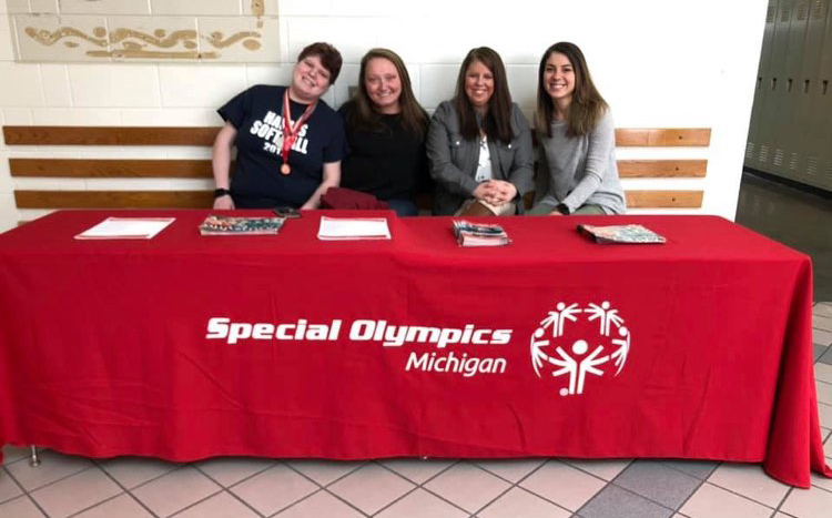 Two athletes and two SOMI staff members sit at a table with a red tablecloth on it.