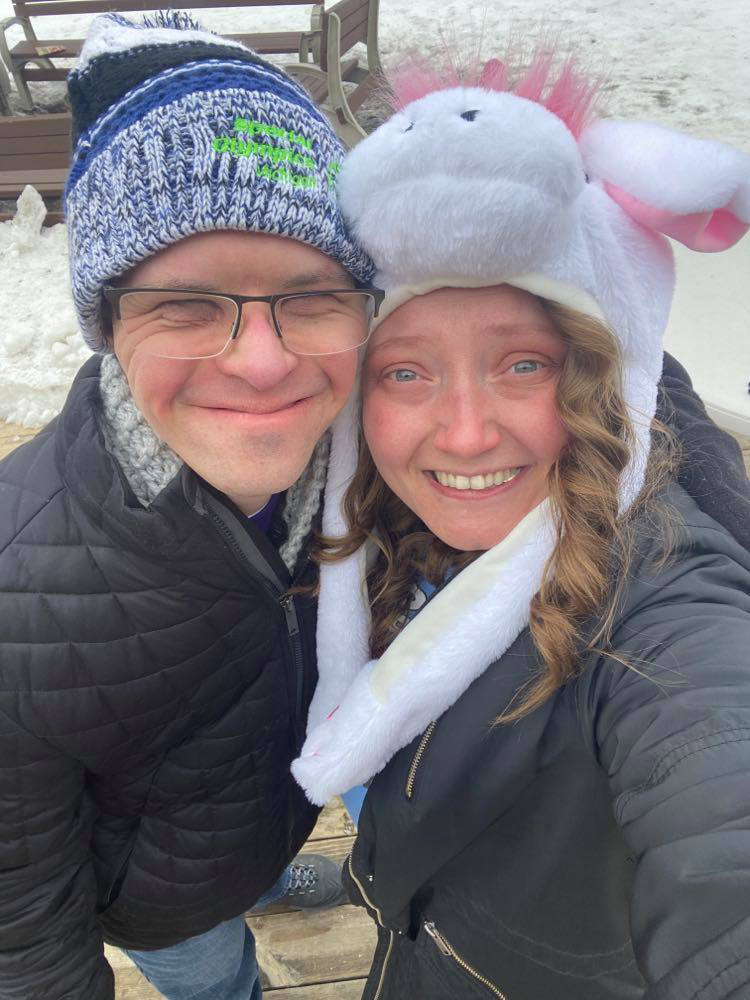 A SOMI athlete and staff member wearing winter hats pose for a photo together.