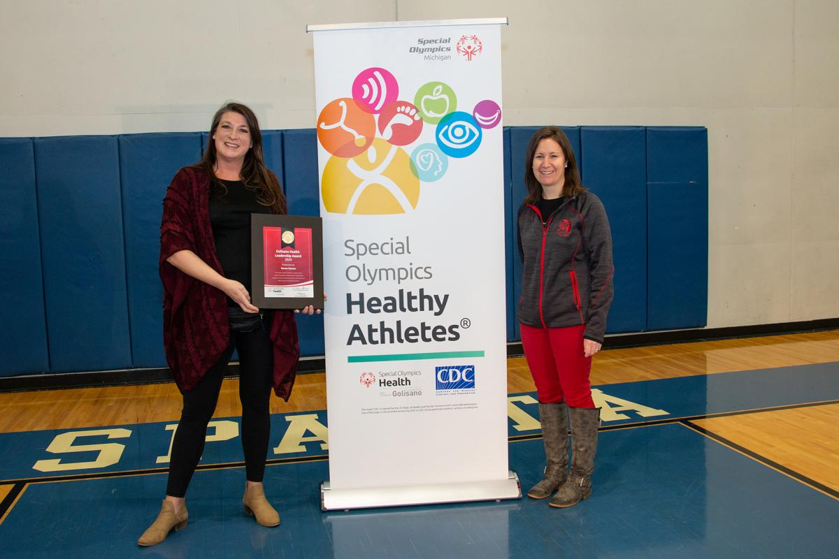 Renne Wyman and Heather Burke stand in front of a Healthy Athletes bannger