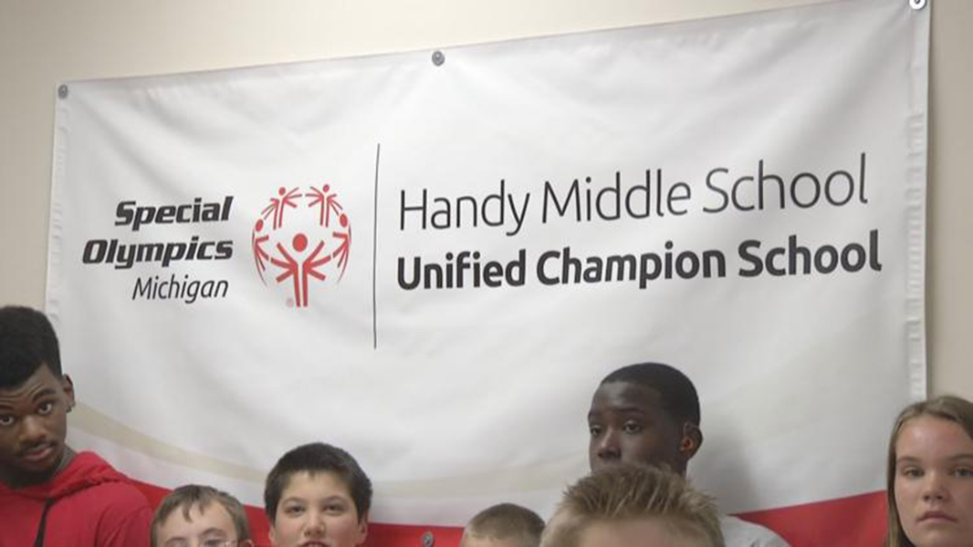 Handy Middle School students stand near a Special Olympics banner