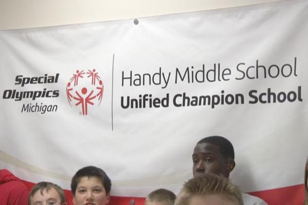 Handy Middle School students stand near a Special Olympics banner