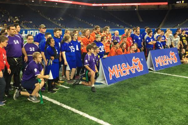 Six Unified high school flag football teams pose for a photo at Ford Field