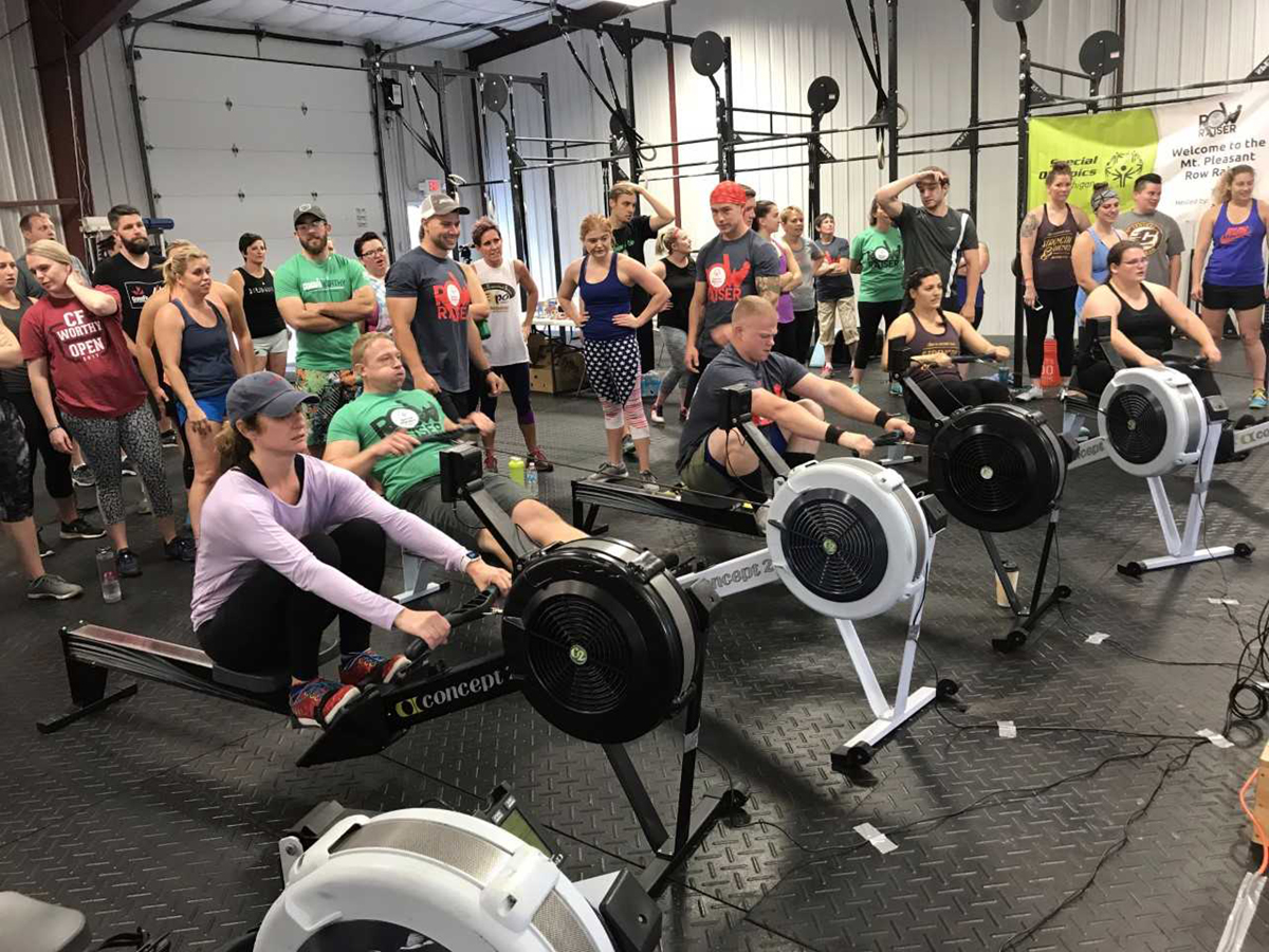 Men and women row on rowing machines