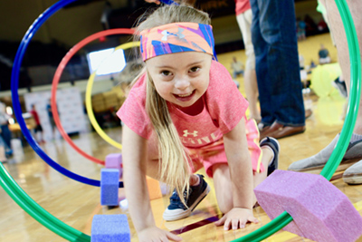 A female Young Athlete crawls through vertical hoops